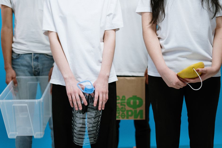 Young adults holding recyclable materials and containers, promoting environmental awareness.